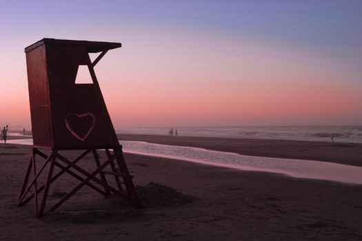 Beautiful quiet sunset at beach. Lifeguard cabin with love sign