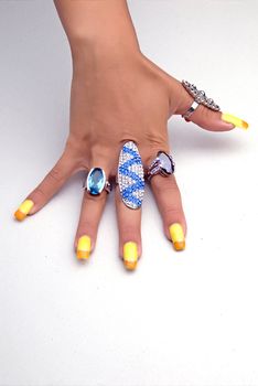 Hand showing big rings on fingers, colored nails