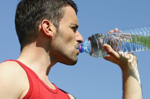 Man is drinking water against blue sky