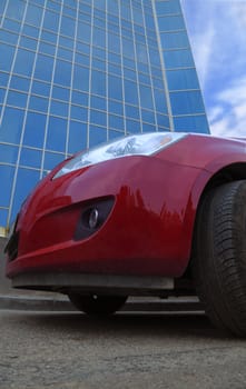 Red business car in front of a corporate building. 