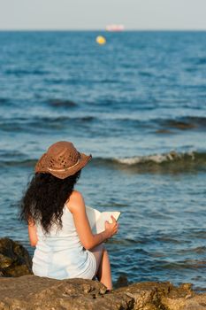 Woman ejoying a book with her feet in the water