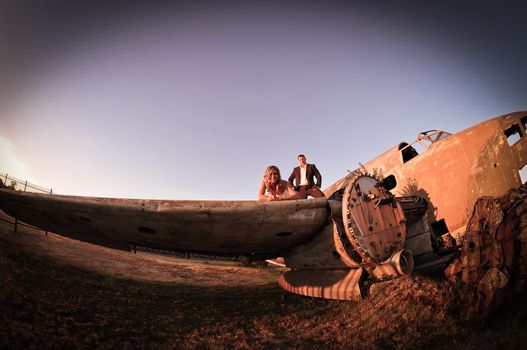 sexy young adult wedding couple standing at crashed DC3 Dakota war plane