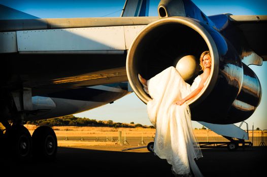 sexy young adult wedding model laying inside the engine intake of  passenger aircraft