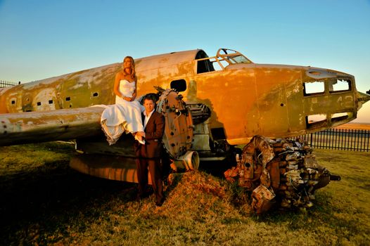 sexy young adult wedding couple standing at crashed DC3 Dakota war plane