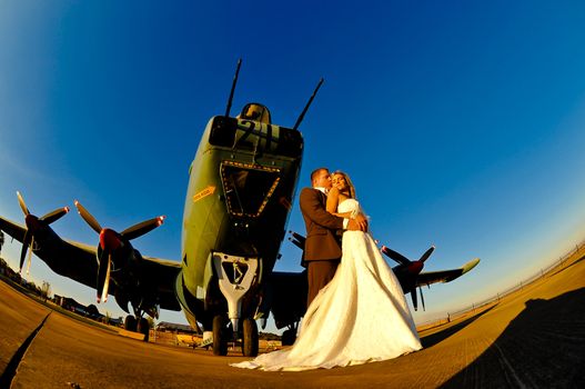 sexy young adult wedding couple standing with old war Albatross aircraft