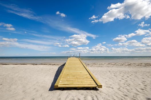 Bridge on beach. The sky is blue with cluds.