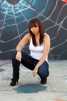 A beautiful young girl with lots of attitude in front of a graffiti spider on his web.