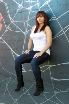 A beautiful young girl with lots of attitude appears to be sitting on a graffiti spider web.