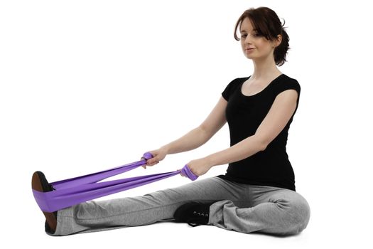 young woman sitting on floor exercising gymastics with a purple ribbon
