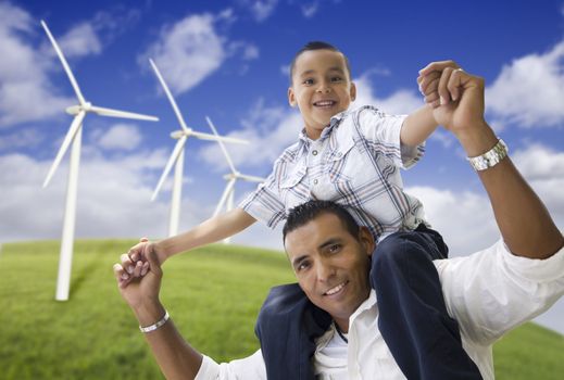 Happy Hispanic Father and Son with Wind Turbine Farm Over Blue Sky.