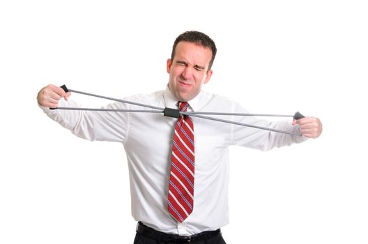 A young businessman straining to stretch a resistance band, isolated against a white background.
