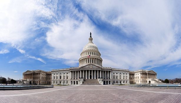 Wide angle panorama of the US United States Capitol building for Democrat Republican Government Senate and House congress parties under a summer blue sky with white clouds.