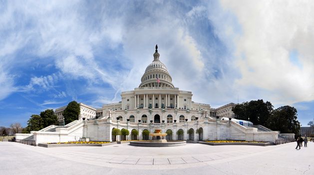 Wide angle panorama of the back of US United States Capitol building where inaugurations of presidents take place for Democrat Republican Government Senate and House parties under a summer blue sky with white clouds.