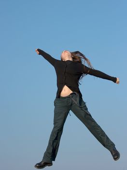 Girl jumping happily under clear blue sky