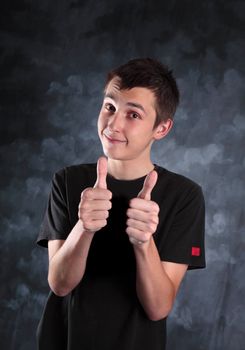 Young teen boy showing both thumbs up on a mottled background.