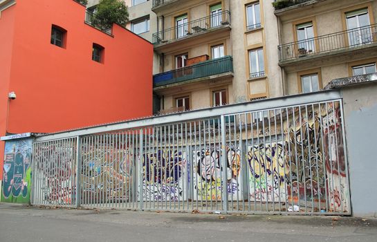 City graffities on parking doors behind the fence of a building