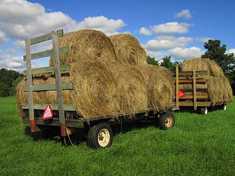 A photograph of two farm wagons loaded with hay.