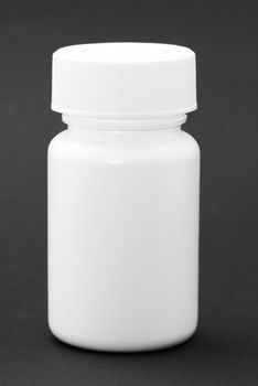White medicine bottle on black background