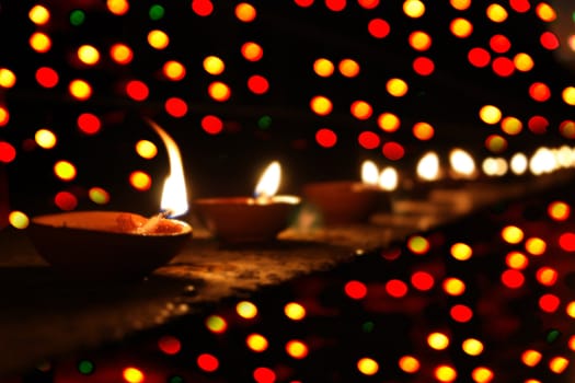 Traditional lamps beautifully arranged near colorful lights, on the occassion of Diwali festival in India.