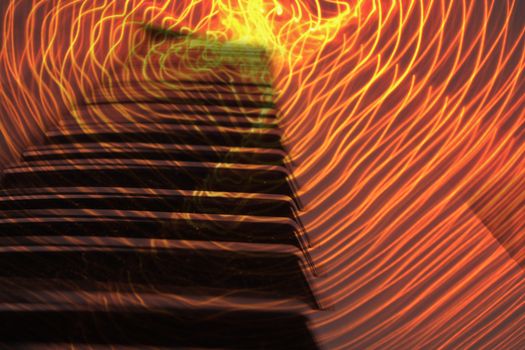 A background of piano keys with an abstract pattern of firey lights.