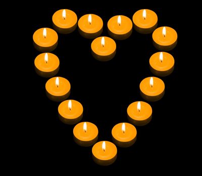 a group of burning candles forming a fiery heart on the black background