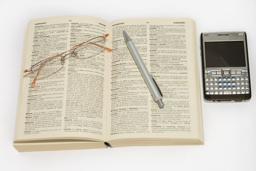 Dictionary glasses and cellphone against white background