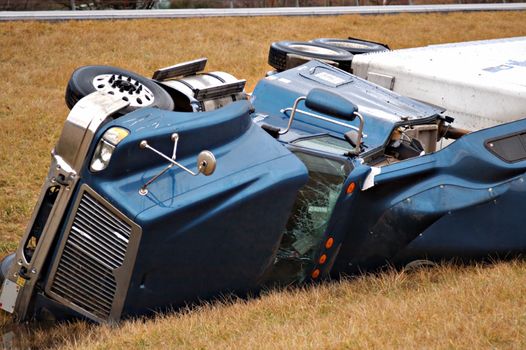 A tractor trailer on its side in the median after a roll over accident. 