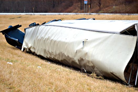 A tractor trailer on its side in the median after a roll over accident. 