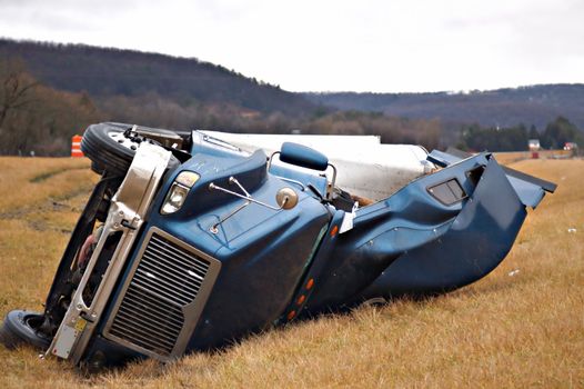 A tractor trailer on its side in the median after a roll over accident. 