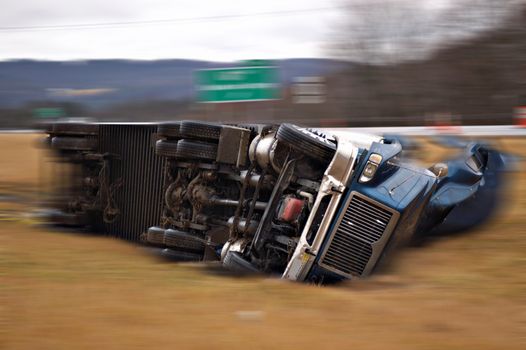 A tractor trailer on its side in the median after a roll over accident. Blur effect added to simulate motion.