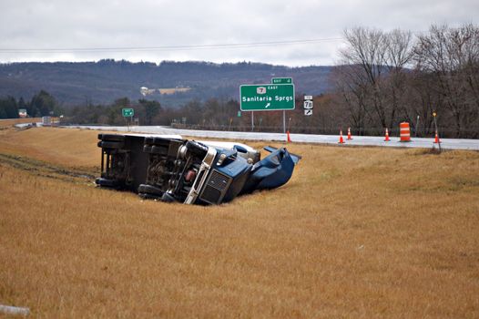 A tractor trailer on its side in the median after a roll over accident. 