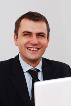 Successful businessman sitting on a table with lap-top smiling