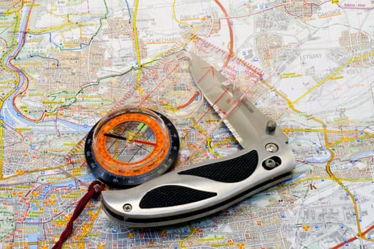 a compass and a knife lying on a map - close up