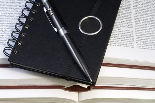 a notebook and a pen lying on the pile of books - close up