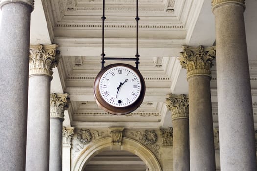 a clock hanging among pillars in the spa colonnade