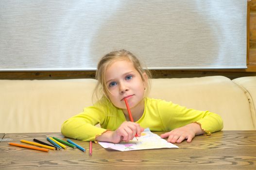 Portrait of the thoughtful lovely girl drawing color pencils.