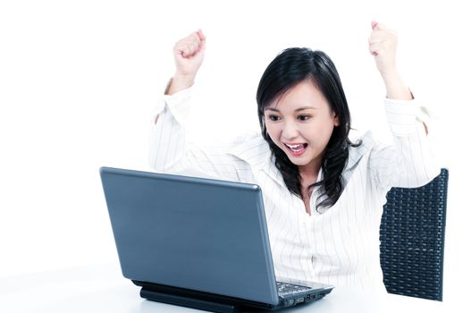 Portrait of a happy young businesswoman cheering in front of laptop, over white background.