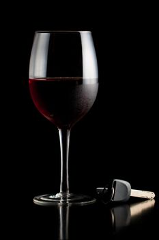 Glass of red wine and car keys on a table or bar.