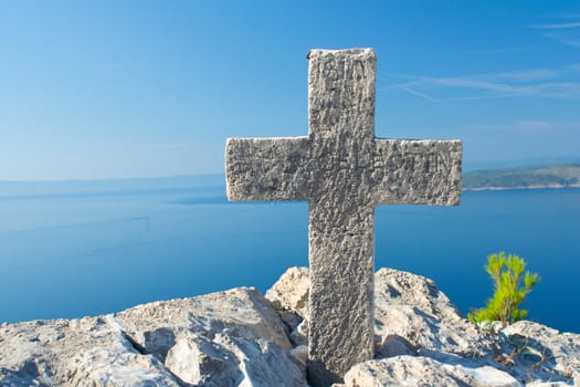White limestone cross on one peak of Biokovo in Croatia. In the background overlooking the sea and islands.