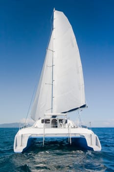 Luxury white catamaran boat in the ocean with blue sky