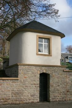 kleines Haus auf einer Mauer aus roten Bruchsteinen errichtet
little house on a wall built of red quarry stone