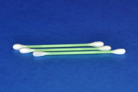 Three wadded sticks for hygiene on a dark blue background