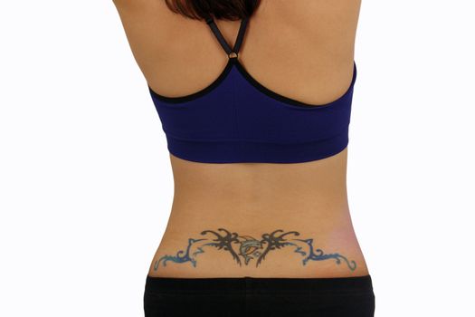 A close-up of a female lower back with a tattoo design, including a dolphin or porpoise jumping over a crescent moon.