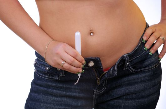 A young woman with camouflage fingernail tips holds a tampon.  Selective focus on the tampon.