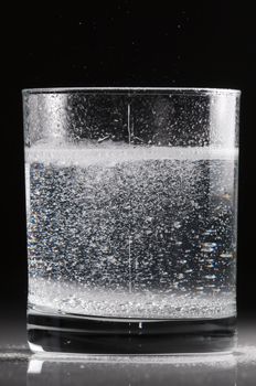 Effervescent pill in a glass of water in backlight