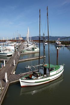 A fishing boat with outriggers raised high moored at a marina, Astoria OR.