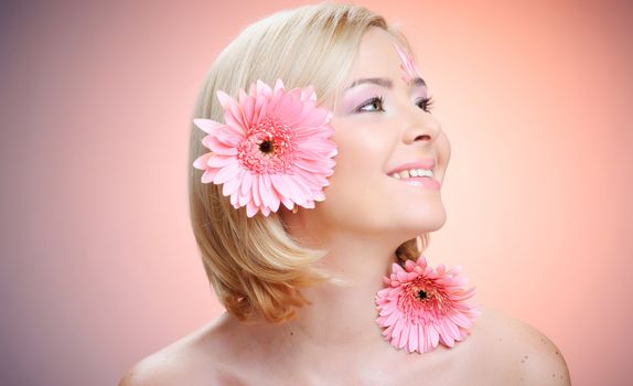 Close-up of woman green eye. Pink flower on background.