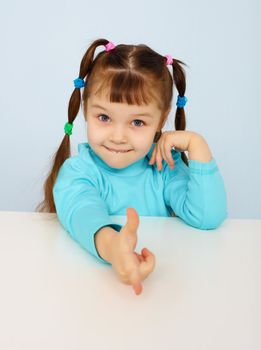 Funny little girl shows a finger on blue background