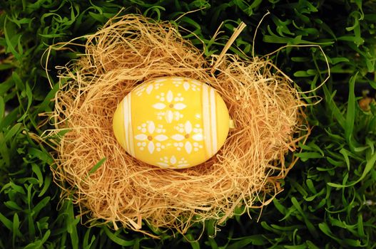 Easter egg in nest on green grass.
