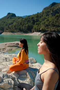 MOther and daughter, yoga at beautiful lakeside setting